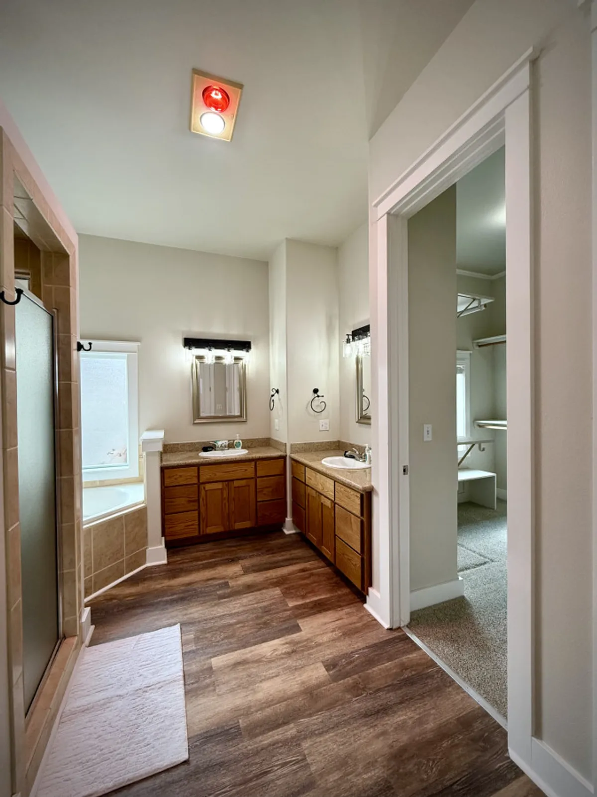 A spa-like ensuite bathroom featuring double vanity sinks, a luxurious bathtub, a spacious shower enclosure, and elegant mirrors—bathed in tranquil, refreshing light.