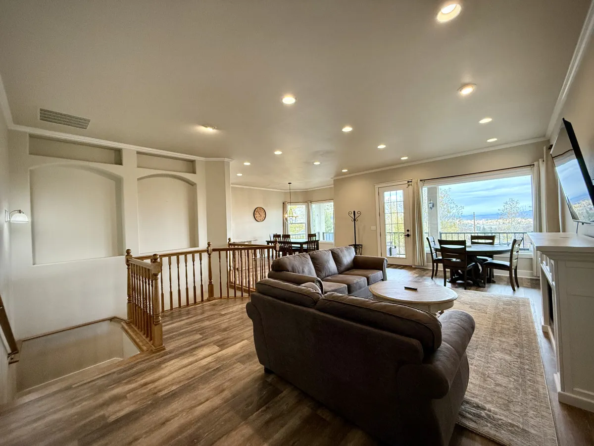 This image showcases a spacious, open-concept living area featuring a comfortable sofa, a coffee table, and a dining area set against large windows that flood the space with natural light. The sunset views out the windows and the arrangement of the furniture suggest a space designed for both socializing and relaxation, ideal for gatherings.
