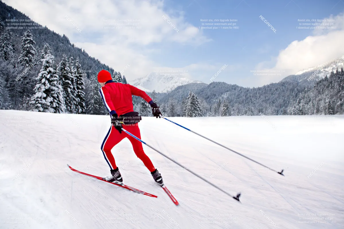 A skier dressed in a vibrant red outfit glides across a snowy landscape, framed by snow-covered trees and majestic mountain peaks in the background. The scene captures the thrill and beauty of winter sports in an alpine setting.